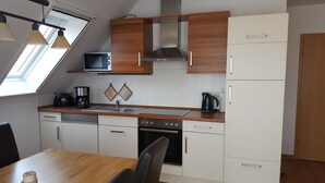 Cocina moderna con microondas, estufa y pileta, muebles de madera y un comedor con mesa y sillas.