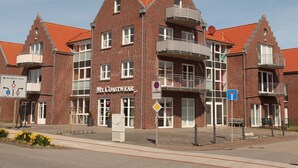 Un bâtiment en briques rouges, sur lequel on peut lire l’enseigne « My Coastwear » et un panneau indiquant « Stationnement interdit ».