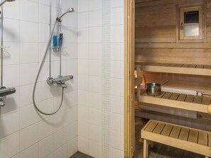 Casa de banho com chuveiro, um banco de madeira e uma prateleira com um vaso.