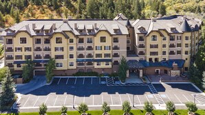 Un hôtel à plusieurs étages doté d’une cour intérieure et d’un parking, entouré de collines boisées.