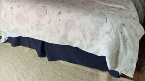 Ein Bett mit einem gemusterten Überwurf und einem dunkelgrünen Wendebezug.