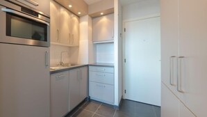 Una cocina moderna con armarios blancos, un horno de acero inoxidable y piso de baldosas.