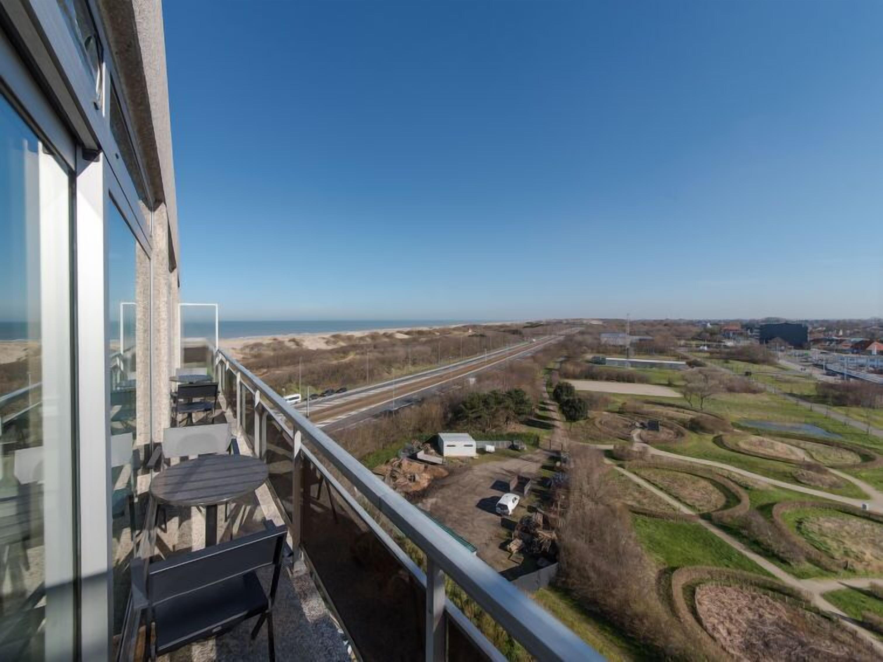 A balcony with a view of a highway and surrounding landscape.