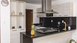 A modern kitchen with a central island, stainless steel appliances, and light wood cabinetry. - Justo Sierra SmartLife (Guadalajara)