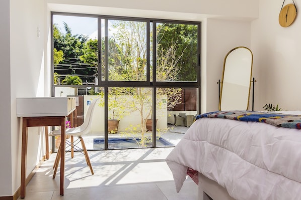 A bedroom with a bed, a desk, and a large window. - Justo Sierra SmartLife (Guadalajara)