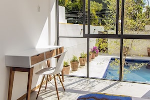 A modern room with a large window, a desk, a chair, and a small pool. - Justo Sierra SmartLife (Guadalajara)