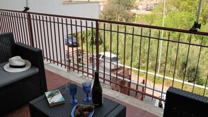 Un balcón con mobiliario de mimbre, una botella y un plato de fresas.