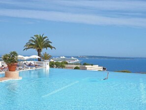 Ein Infinity-Pool mit Blick auf das Meer und einem Kreuzfahrtschiff im Hintergrund.