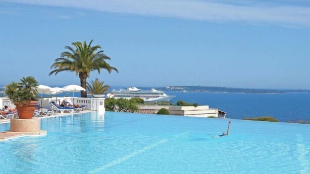 Una piscina infinita con vistas al mar y un crucero al fondo.