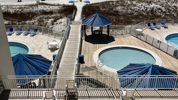 A pool area with lounge chairs, umbrellas, and a gazebo overlooking the beach.