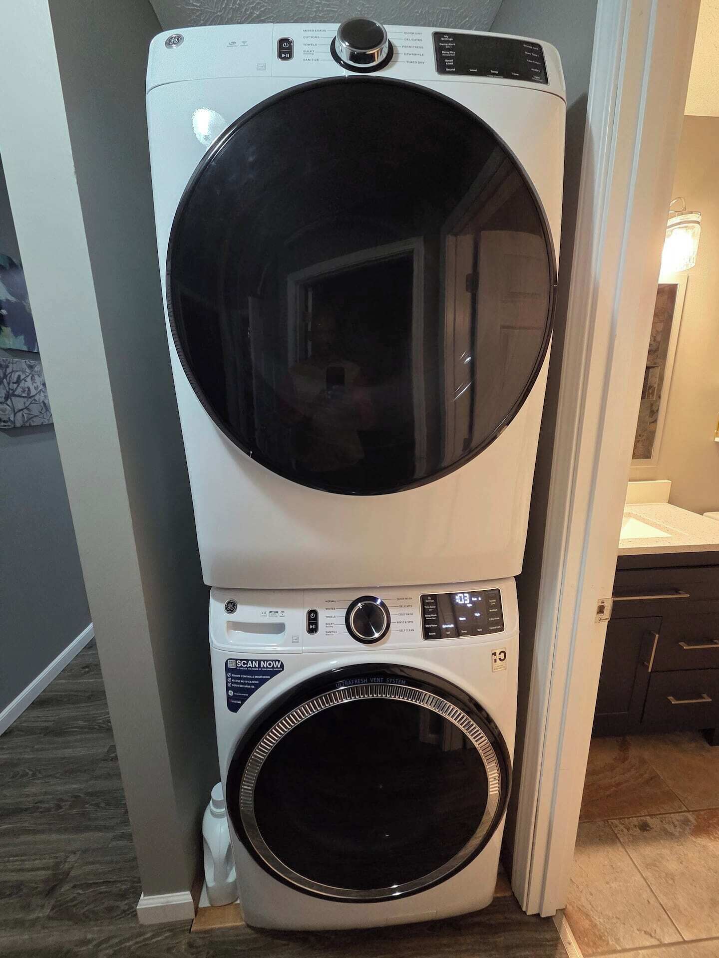 A stacked washer and dryer unit with a control panel, a water inlet, and a drain hose.