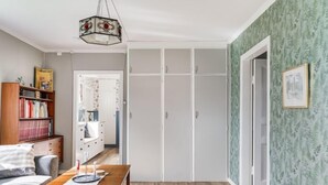 A room with a wooden floor, a wooden table, a sofa, a bookshelf, and a wardrobe with white doors. - Vacation home Hultet by Interhome (Mullsjö)