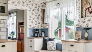 A kitchen with white cabinetry, a window seat, and floral wallpaper. - Vacation home Hultet by Interhome (Mullsjö)