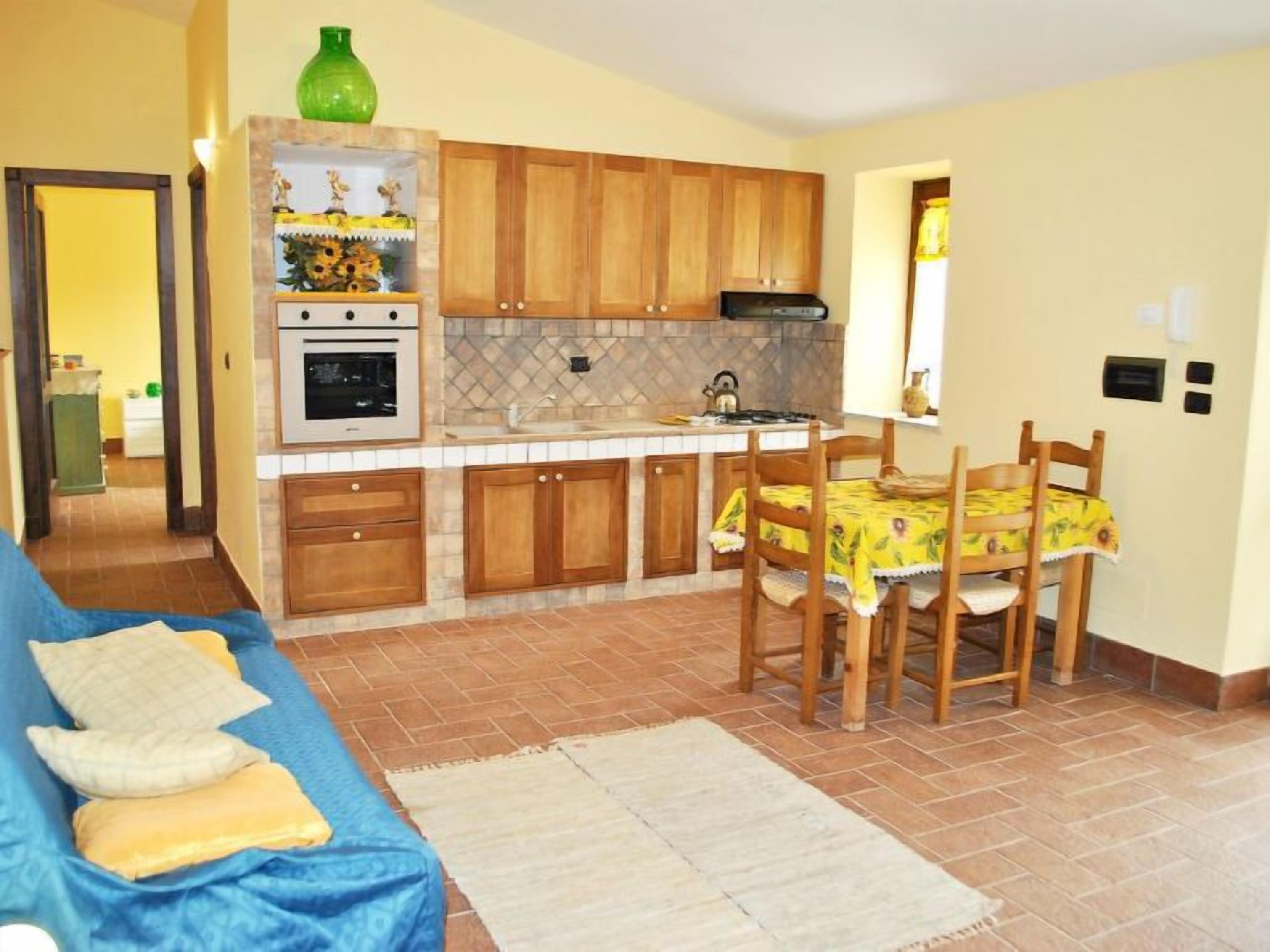 Una cocina compacta con armarios de madera, horno empotrado y comedor con mesa y sillas.