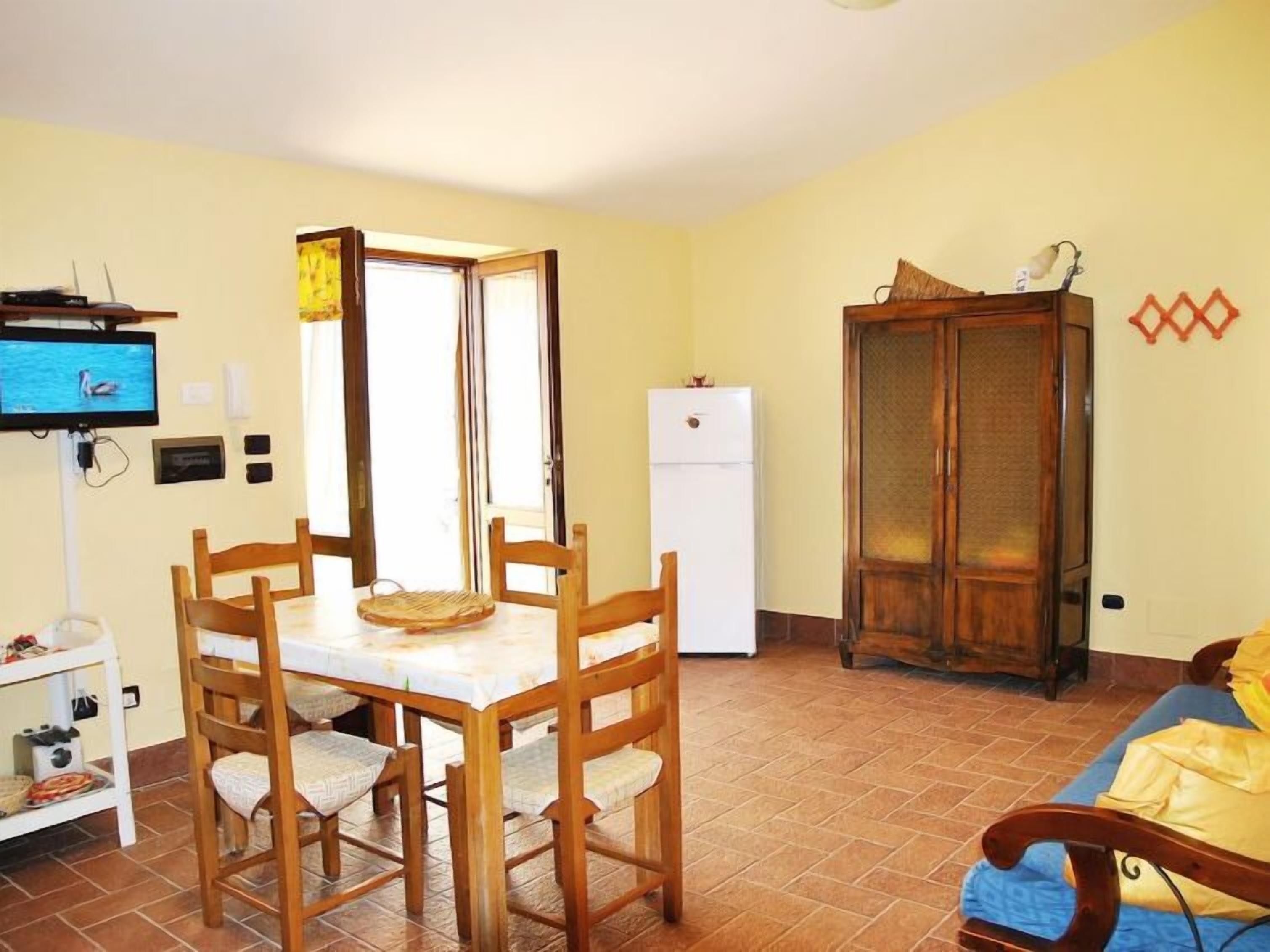 Un espacio habitable compacto con una mesa de comedor, sillas, un refrigerador, un armario y un televisor.