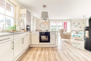 A modern kitchen with a built-in oven, a clock, and a large window.