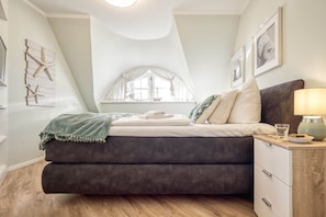 A bedroom with a bed, a nightstand, a lamp, and a window with curtains.