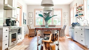 A spacious kitchen with a central island, wooden flooring, and a large pendant light. - Steps to Downtown, Pier & Beach with Gourmet Kitchen! (Folly Beach)