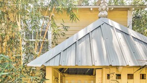 A yellow wooden structure with a metal roof, a staircase leading to an upper level, and a small window. - Steps to Downtown, Pier & Beach with Gourmet Kitchen! (Folly Beach)