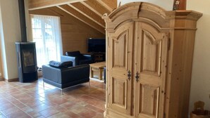 A spacious living area with a fireplace, a large wooden cabinet, and a television. - Fichte (Sulliger) by Interhome (Saanenmöser)