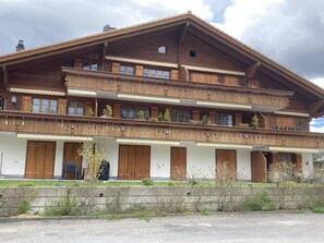 A multi-story wooden chalet with balconies, large wooden doors, and a sloped roof. - Fichte (Sulliger) by Interhome (Saanenmöser)