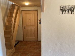 A wooden staircase leading to a door with a tiled floor. - Fichte (Sulliger) by Interhome (Saanenmöser)