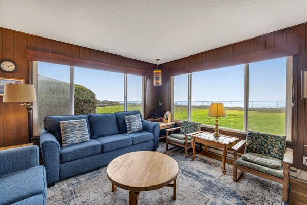 Relax in a spacious living room with a comfortable sofa, armchairs, and a coffee table, offering a view of the lush landscape.