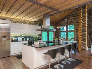 A modern kitchen with a central island, bar stools, and a stainless steel refrigerator.