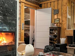 Um quarto com lareira, parede de madeira, porta branca e uma estante com copos.