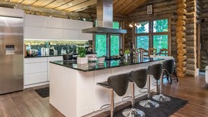 Een moderne keuken met een centraal eiland, barstoelen en een groot raam met uitzicht op de omgeving.