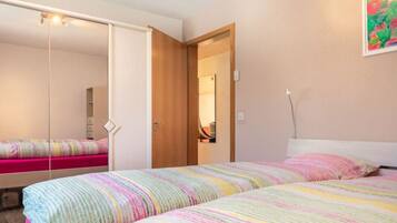 Ein Schlafzimmer mit Bett, Kleiderschrank, Tür und Spiegel.