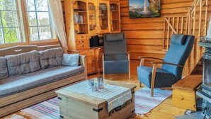 A cozy log cabin interior with a sofa, armchairs, a television, and a fireplace. - Iltaranta by Interhome (Joutsa)