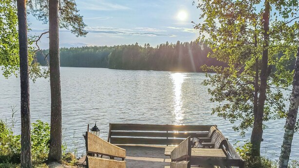 A wooden dock leading to a bench overlooking a calm lake, surrounded by trees. - Iltaranta by Interhome (Joutsa)