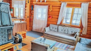 A cozy cabin interior with a stone fireplace, wooden furniture, and a sofa. - Iltaranta by Interhome (Joutsa)