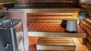 A rustic cabin interior with a wood-burning stove, a brick fireplace, and a tiled floor. - Korvenpää by Interhome (Joutsa)