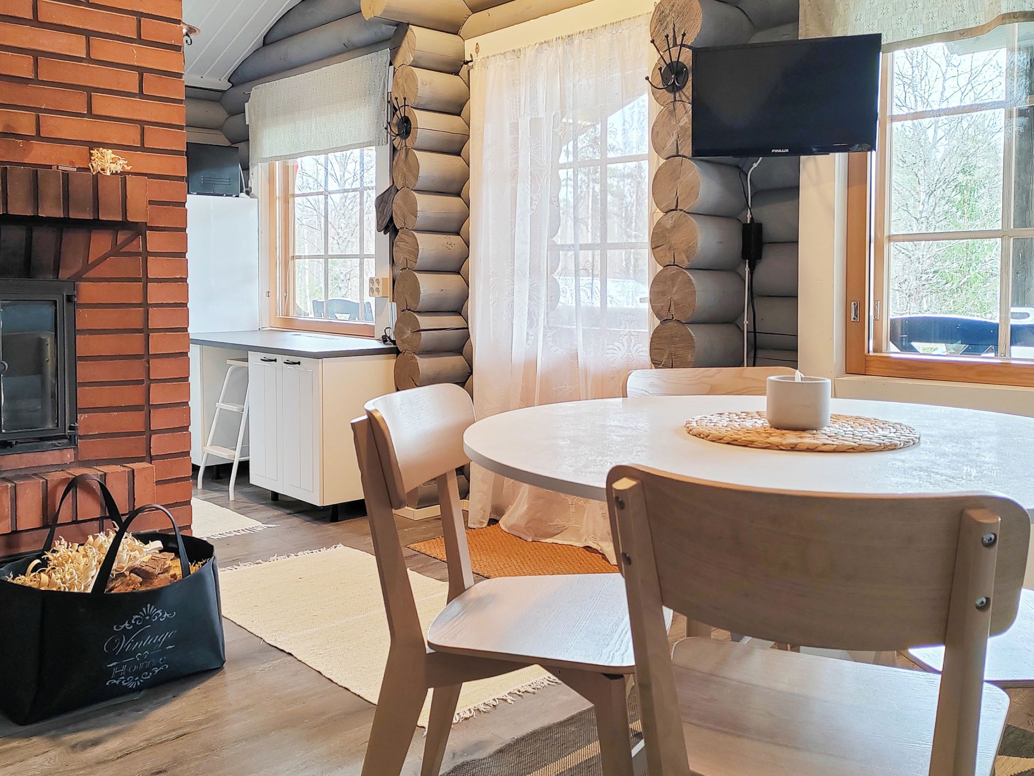 A cozy interior with a round table, chairs, a fireplace, and a television.