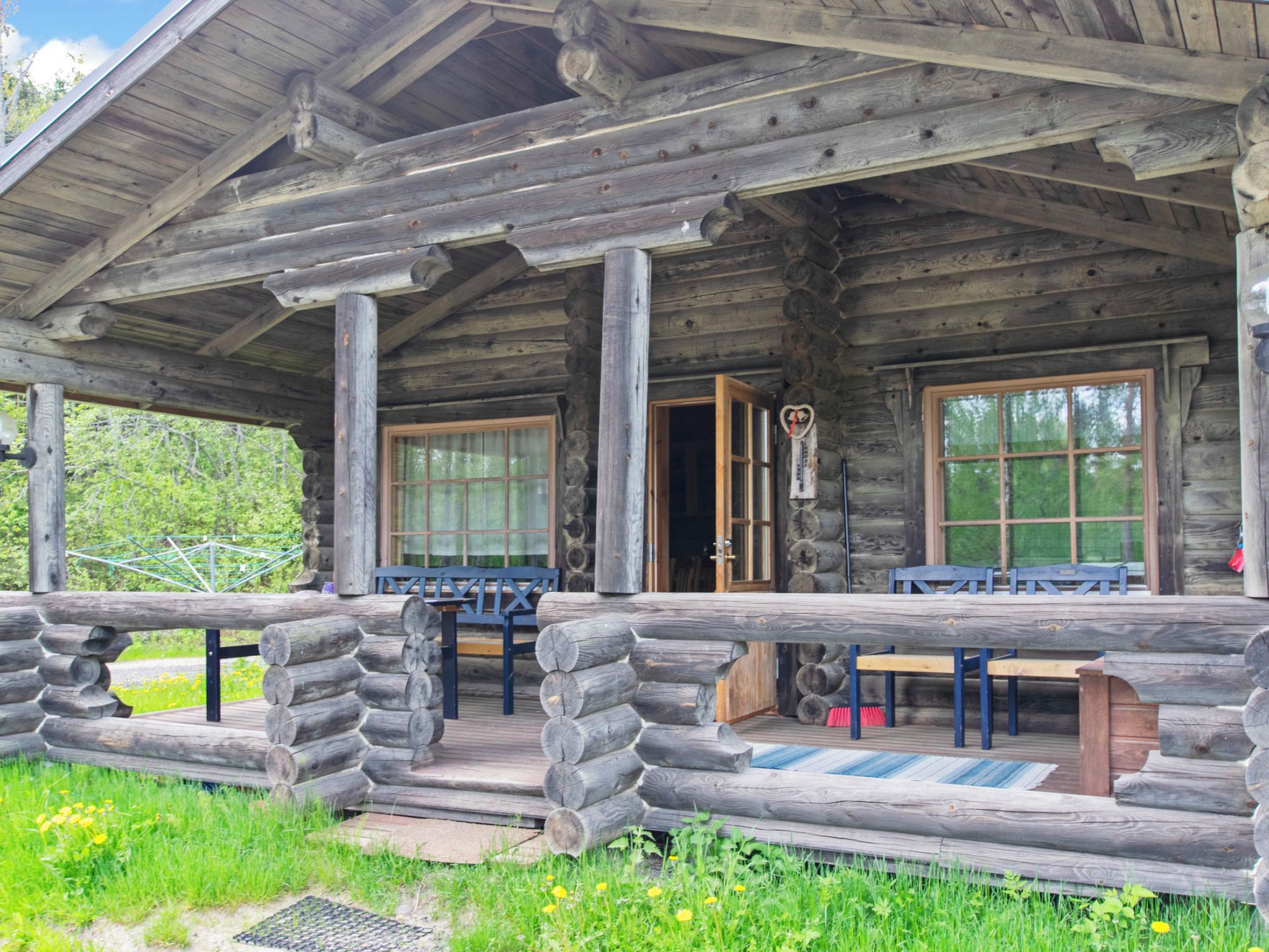 A log cabin with a porch, a table, and chairs.