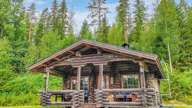 A rustic log cabin with a porch, large windows, and a chimney. - Korvenpää by Interhome (Joutsa)