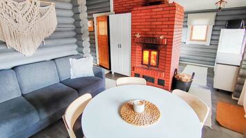 A modern living room with a grey sofa, a white table with a woven placemat, and a red brick fireplace.