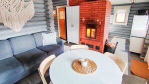 A cozy living area with a blue sofa, a round white table with a candle, and a red brick fireplace. - Korvenpää by Interhome (Joutsa)