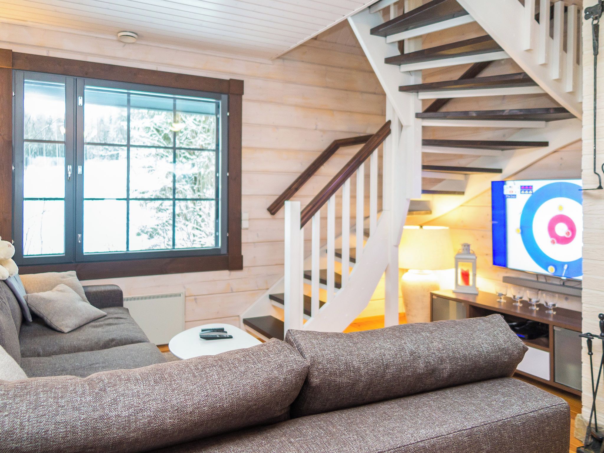 Ein gemütliches Wohnzimmer mit einer Couch, einem kleinen Tisch und einer Treppe, die in eine andere Etage führt.