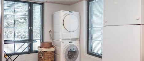 Un lavadero pequeño con lavadora de carga frontal, secadora y refrigerador.