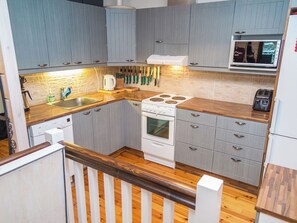 A compact kitchen with grey cabinets, a white stove, and a microwave.