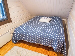 Une petite pièce agréable, avec un lit simple, une fenêtre et un plancher en bois.