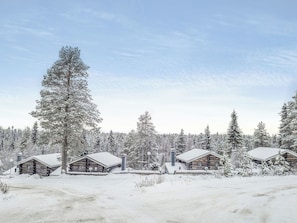 Et feriested med hytter i træ, omgivet af en snedækket skov.