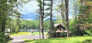 A cabin with a porch and a view of a lake and mountains.