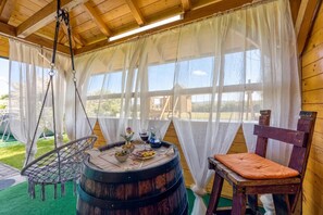A rustic wooden room with a hanging chair, a wooden barrel, and a table set with food and drinks. - Merry's House w/ Pool & Sauna, Gradac, Slovenia (Gradac)
