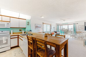 Enjoy meals in the kitchen with modern appliances, a dining table, and a balcony offering a view.