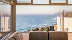 Een balkon met uitzicht op zee, een bank en een schoorsteen.