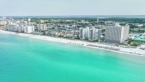 Un hotel costero con varios edificios altos, una playa y un puerto deportivo.